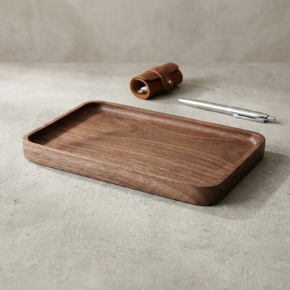 Wooden tray on a beige surface with a pen and small leather item.