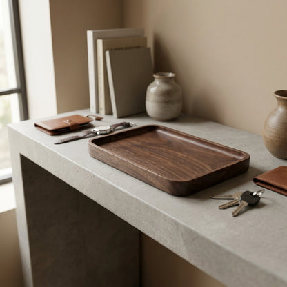 Wooden tray on a concrete surface with books, a vase, and keys.