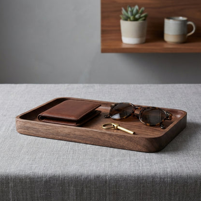 Wooden tray with wallet, sunglasses, and key on a gray surface with a blurred background